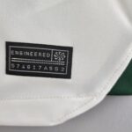Close-up of a black sewn brand patch on white fabric, partially reading 'ENGINEERED' with a small emblem next to it.
