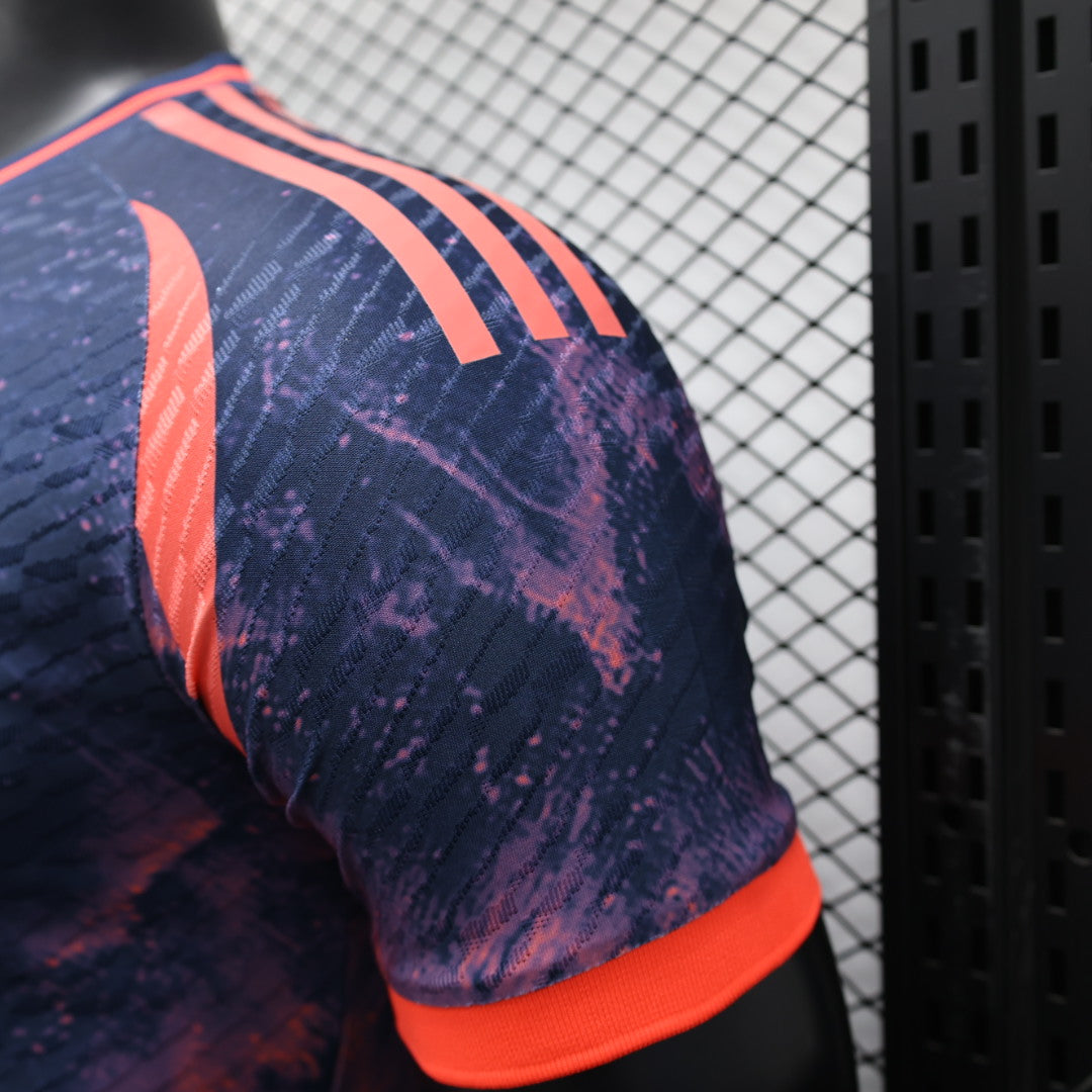 0b616aab | UAE SPORT STORE Close-up of a purple athletic jersey shoulder with bright orange stripes, wearing against a chain-link fence background.
