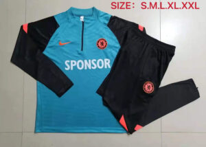 Chelsea FC training kit laid out: turquoise jersey with black sleeves, sponsor text 'SPONSOR', and club crest; paired with black shorts/pants with pink accents.