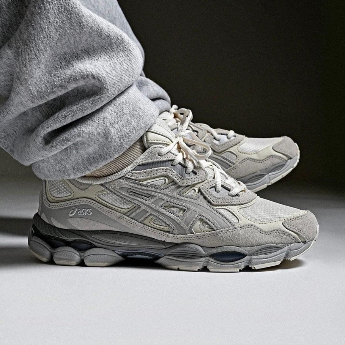 Gray Asics running sneakers with a chunky sole, worn with light gray sweatpants/leggings.