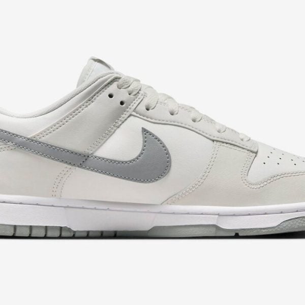 White Nike sneaker with light gray swoosh, low-cut design, and white midsole viewed from the side.