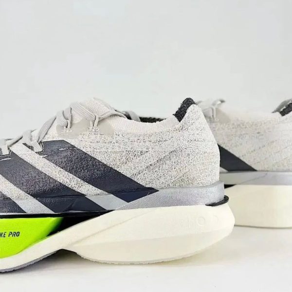 Pair of gray running shoes with neon lime green heel detail and a textured upper, shown from the side.