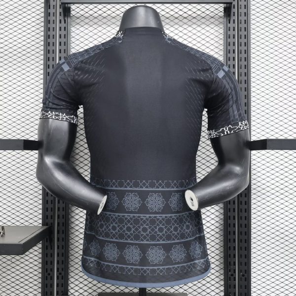 Back view of a dark athletic shirt on a mannequin in a metal rack, showcasing patterned sleeves and hem in a gym display.