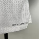 Close-up of white patterned chair fabric with the text DRI-FIT/ADV and part of a black chair leg visible to the left.