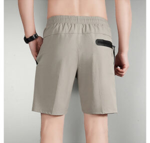 0d21fa8e | UAE SPORT STORE Back view of beige elastic-waist shorts with a black zippered pocket on the right rear side.