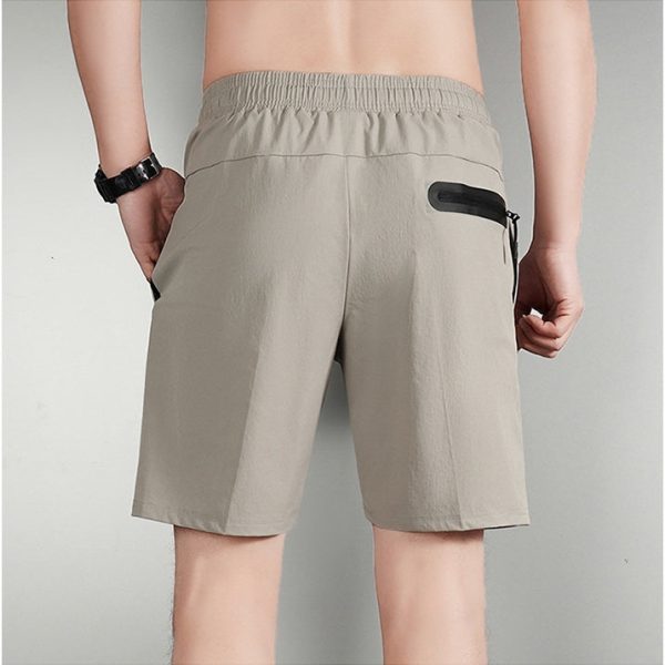 Back view of beige elastic-waist shorts with a black zippered pocket on the right rear side.