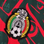 0da24bd1_f336008b-ec5e-4684-9268-ceaa36f28b27 | UAE SPORT STORE Close-up of an embroidered patch with the Mexican coat of arms (eagle and snake) in a circular border on green fabric with red accents.