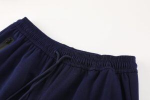 Close-up of a navy blue fabric waistband with an elastic band and drawstring, showing a zippered pocket edge.