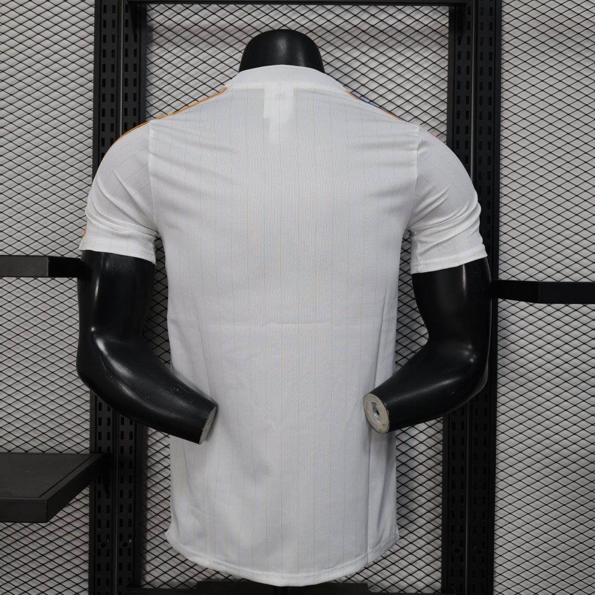 Back view of a white pinstriped shirt on a black mannequin torso against a metal grid shelving background.