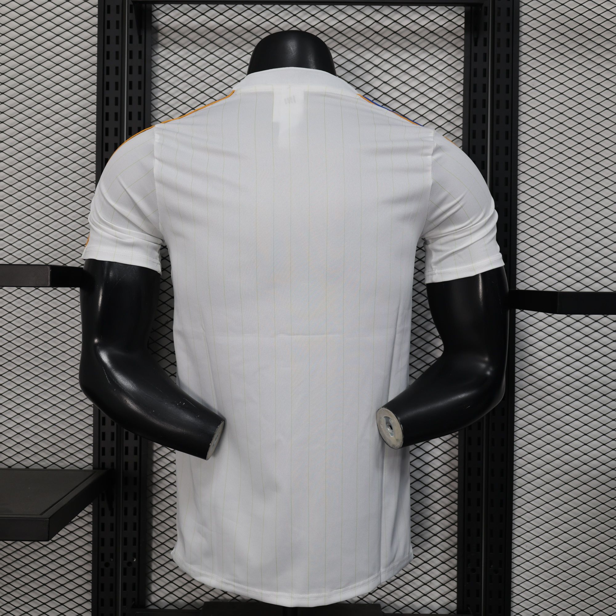 0deafdb9 | UAE SPORT STORE Back view of a white pinstriped shirt on a black mannequin torso against a metal grid shelving background.