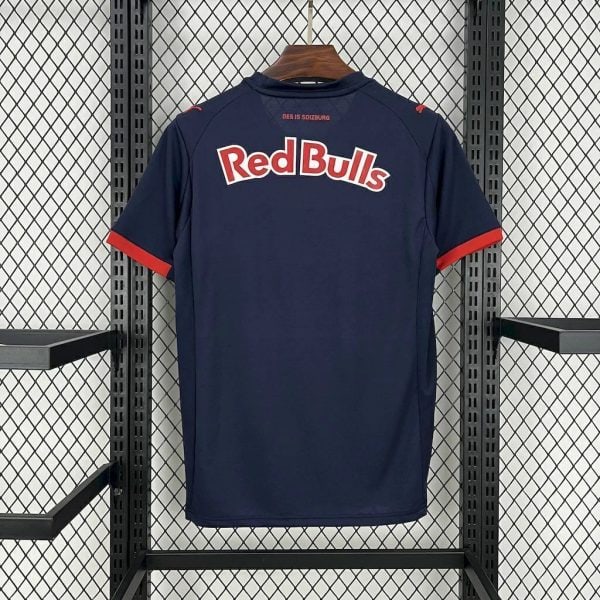 Navy Red Bulls sports jersey with red sleeve trim on a wooden hanger against a metal grid display.