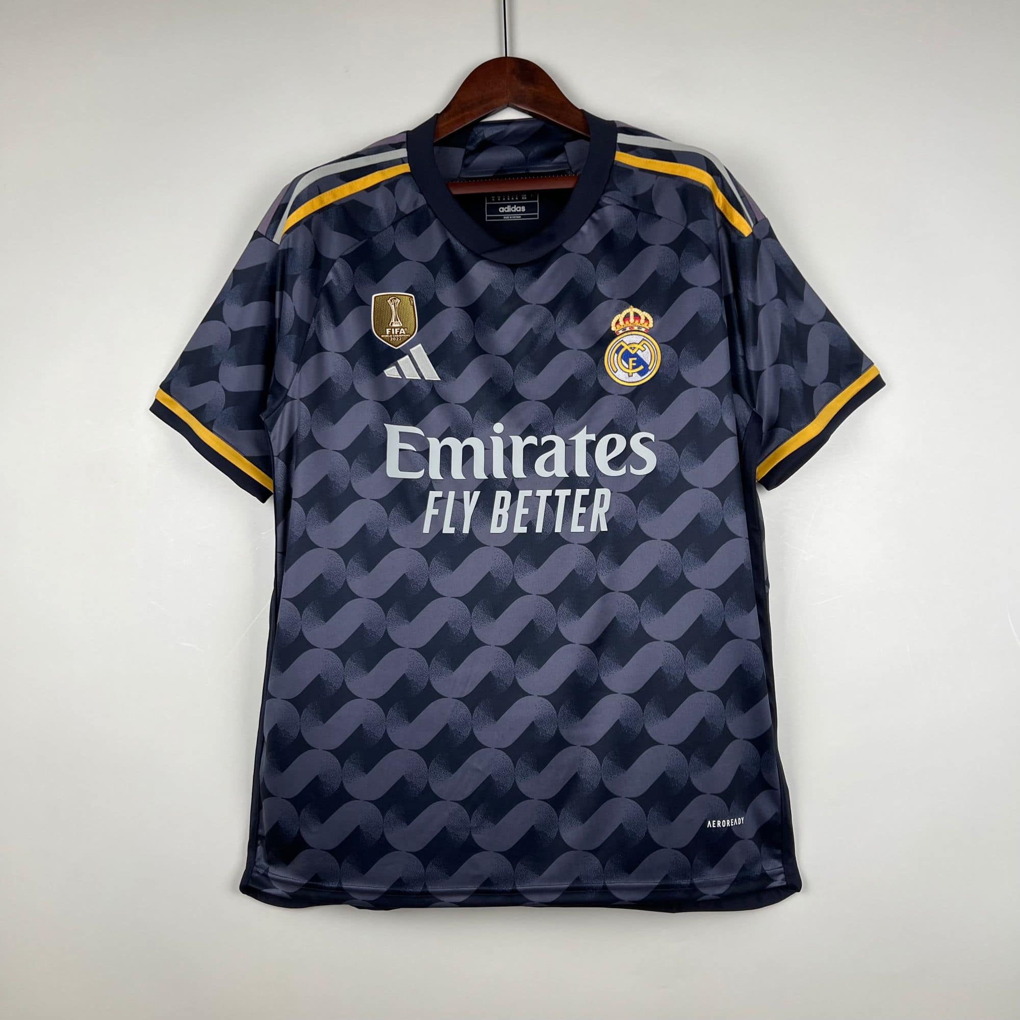 0f22ba77_1 | UAE SPORT STORE Dark blue Real Madrid football jersey on a hanger, featuring Adidas logo, crest, FIFA World Champions 2022 badge, and Emirates sponsor.