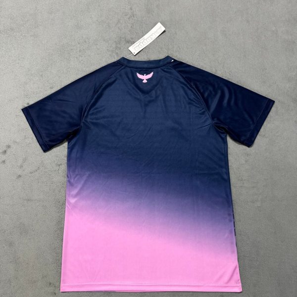 Navy T-shirt with a pink gradient fading to magenta at the bottom; small pink bird logo at the back neck and a white tag above.