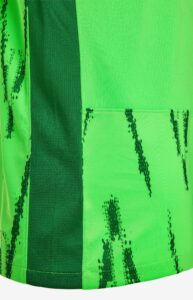 0uQ1E1yvfQEPH7W | UAE SPORT STORE Close-up view of a high-visibility lime-green vest fabric with a dark green vertical stripe and stitched pocket seam, showing a textured mesh pattern.