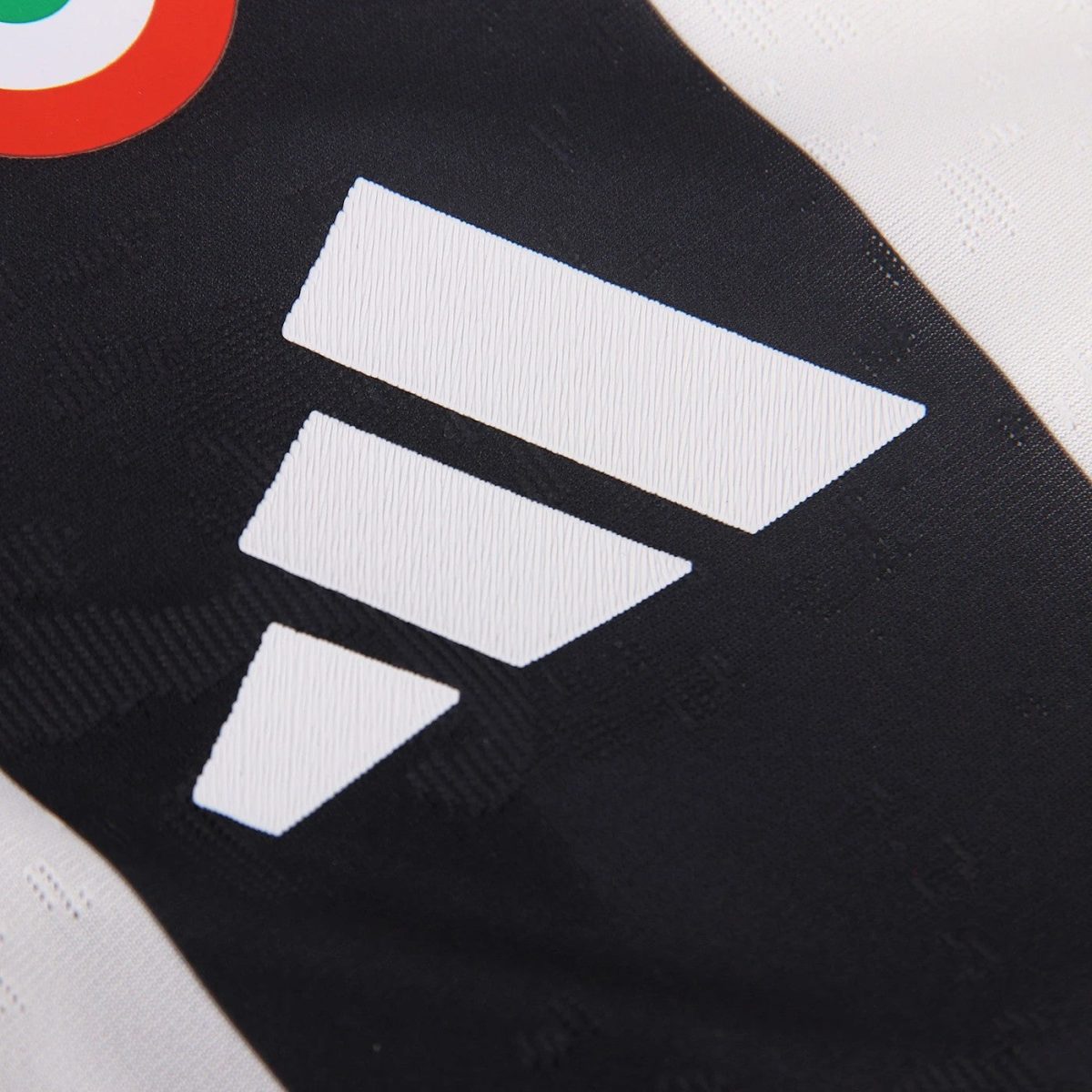 Close-up of white fabric patches forming three diagonal chevrons on black athletic material (sports jersey).