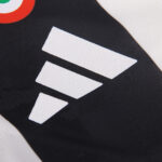 Close-up of white fabric patches forming three diagonal chevrons on black athletic material (sports jersey).