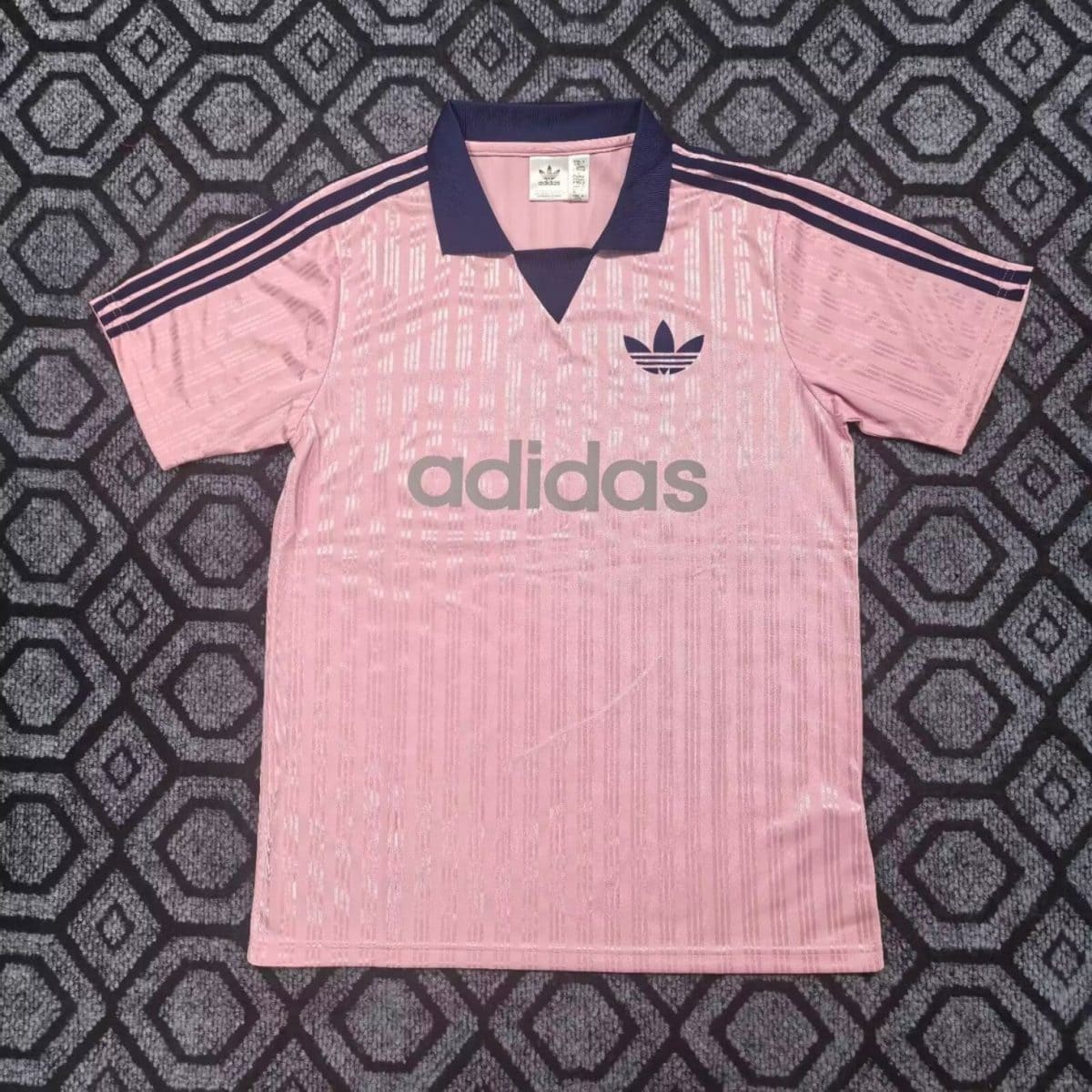 Pink Adidas polo shirt with navy collar and three navy stripes on sleeves, large gray Adidas logo across the chest.