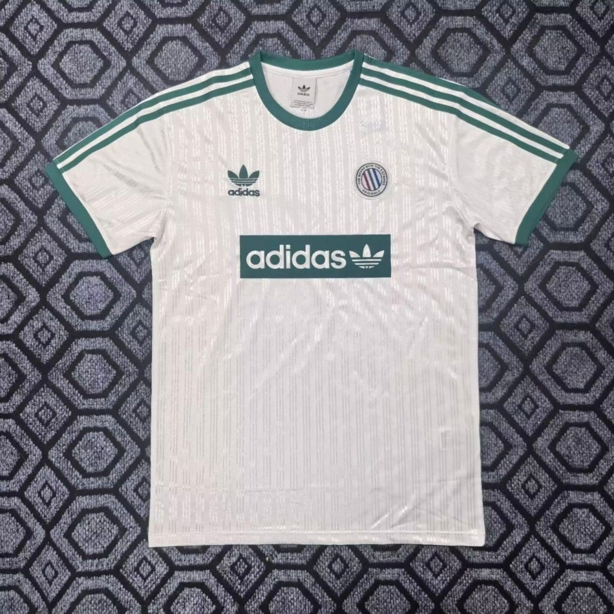 White Adidas soccer jersey with green trim, three green stripes on the shoulders, Adidas logo on the chest, and a circular club crest on the left.
