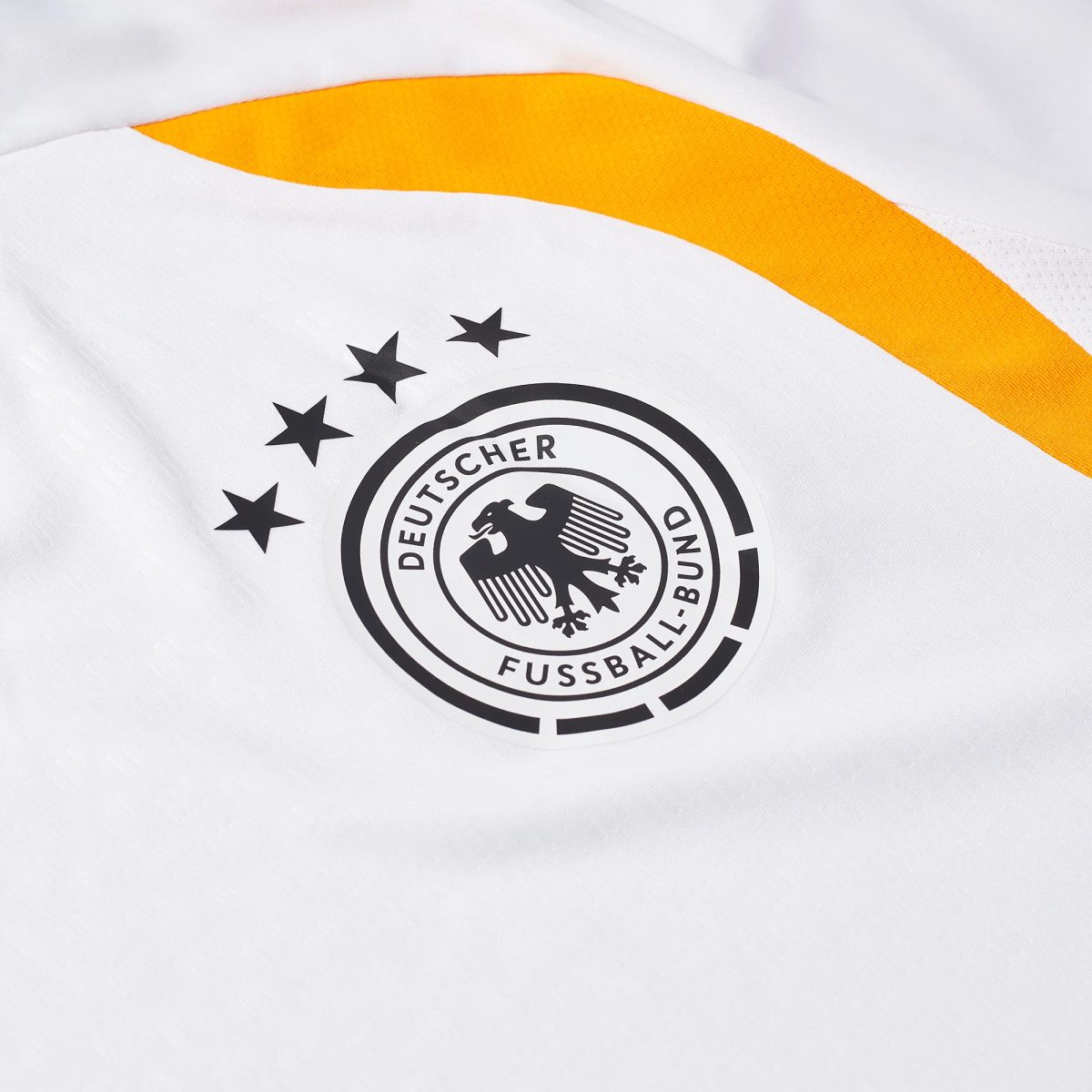 Close-up of white fabric with an orange curved stripe and a partial black circular seal reminiscent of a football federation logo (Deutscher Fußball-Bund).