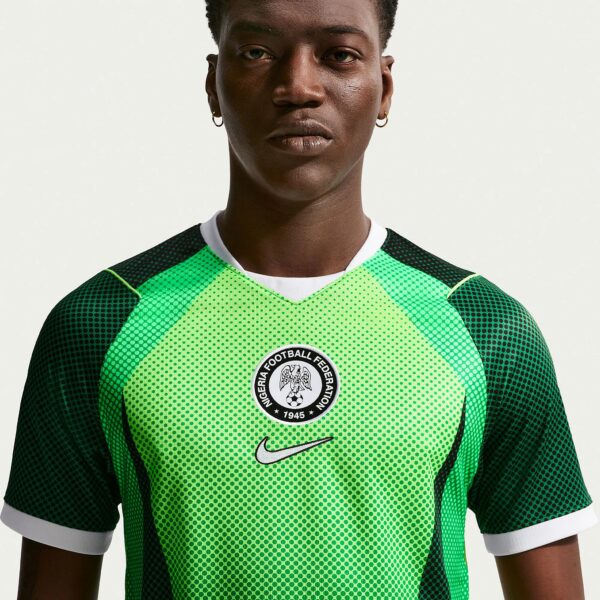 Close-up of a person wearing a green dotted soccer jersey with a circular Nigeria Football Federation badge on the chest