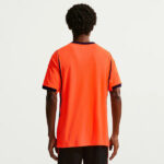 1053643_gallery_1 | UAE SPORT STORE Back view of a person wearing an orange athletic jersey with navy trim on the sleeves and collar, standing against a plain light background.