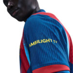 Close-up of a person wearing a blue striped jersey with red accents; the sleeve shows the text 'AMBILIGHT tv'.
