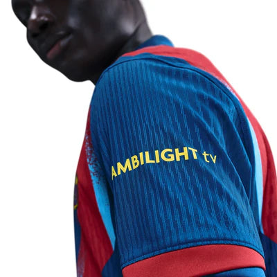 Close-up of a person wearing a blue striped jersey with red accents; the sleeve shows the text 'AMBILIGHT tv'.