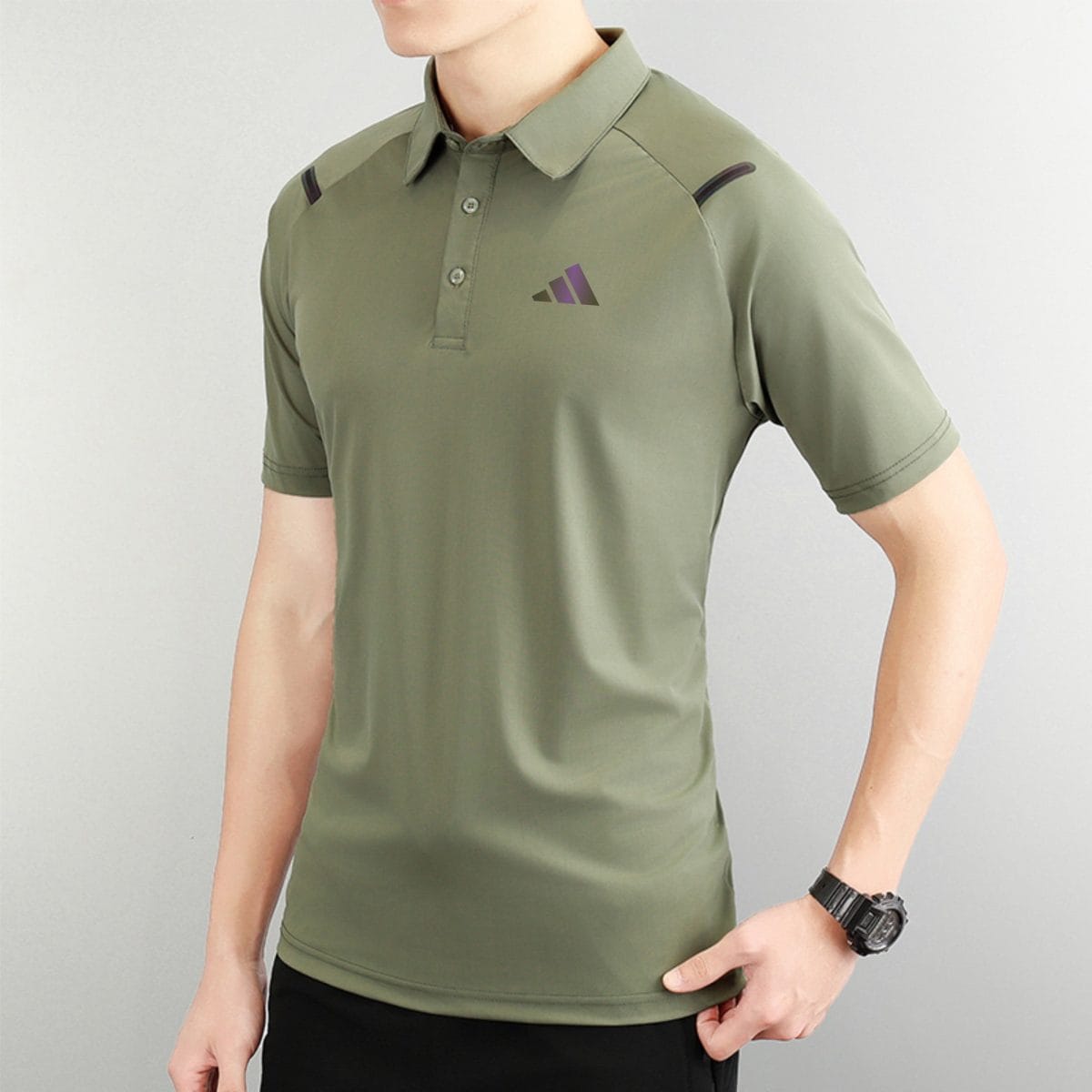 Person wearing an olive polo shirt with a small purple logo on the left chest, against a light background.