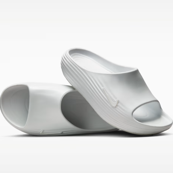 Pair of white open-toe slides with a textured strap and a Nike swoosh on the side.
