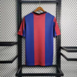 Blue and red vertical-striped soccer jersey on a hanger, displayed against a metal rack backdrop.