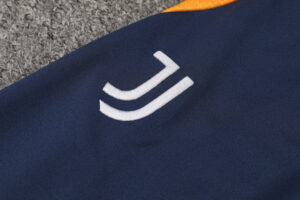 Close-up of dark blue fabric with a white double-curve logo and an orange edge at the top.