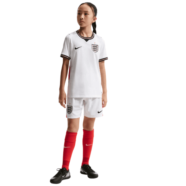 111_881f098b-4b5c-4e12-93be-66b5ea287ebc - UAE SPORT STORE Girl wearing England women’s soccer kit: white jersey with crest, white shorts, red socks, black cleats.