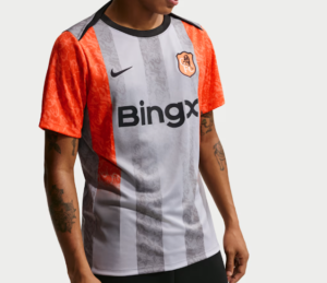 Person wearing a gray-and-white striped soccer jersey with red sleeves, featuring a BingX sponsor logo and team crest.