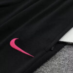 Close-up of black fabric with a bright pink Nike swoosh embroidery near a zipper edge.