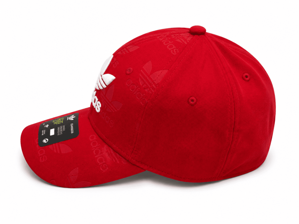 Red Adidas baseball cap with embossed logo pattern and curved brim, tag visible on the brim