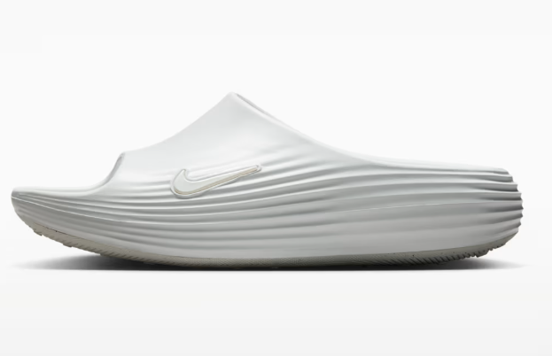 White slip-on Nike running shoe with a sculpted, ribbed midsole, side view