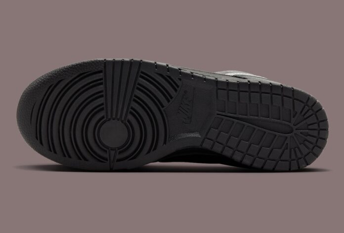 Bottom view of a black sneaker showing its tread pattern and sole design