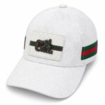 White Gucci baseball cap with GG pattern, green–red–green stripe, and a white patch featuring a black bee and Gucci logo.