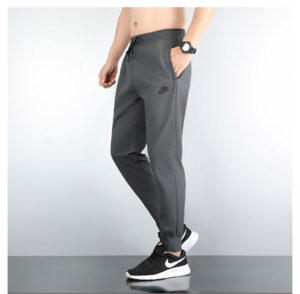 Side view of a person wearing gray Nike joggers with a drawstring waist and side pockets, paired with black and white Nike sneakers.