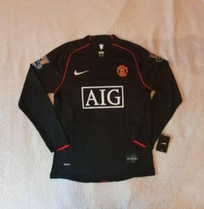 12_e6ad788b-eb7b-4f82-8e4e-56c5bccf9f72 | UAE SPORT STORE Black Manchester United long-sleeve jersey with red piping, AIG sponsor logo, and club crest on the left chest; Nike swoosh on the right sleeve edge, laid flat on a light surface.
