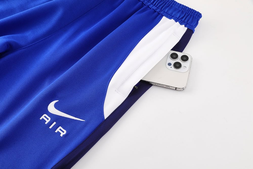 12c65614 | UAE SPORT STORE Blue athletic joggers with a white side stripe and Air logo, a smartphone tucked into the back pocket visible.