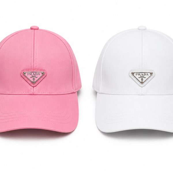 Two Prada baseball caps side by side: pink on the left and white on the right, each with a triangular logo patch on the front.