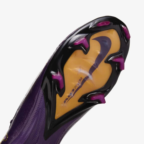 Purple soccer cleat outsole with magenta studs and a yellow inner sole, showing Nike Mercurial branding.