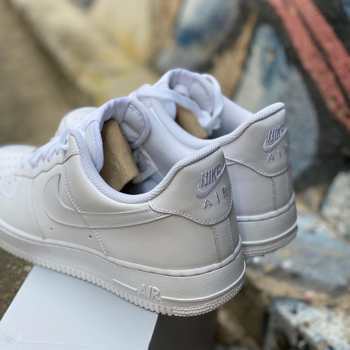 White Nike Air Force 1 sneakers, close-up of the heel with embroidered Nike Air logo on the back tab.