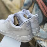 White Nike Air Force 1 sneakers, close-up of the heel with embroidered Nike Air logo on the back tab.