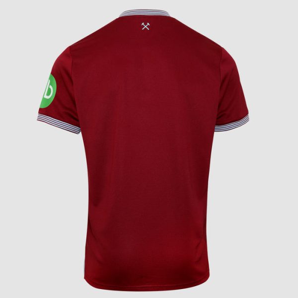 Back view of a red polo shirt with white-and-navy striped collar and sleeve cuffs, small crossed-tools logo at the neck, and a green circular patch on the left sleeve