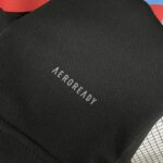 Close-up of black textured fabric with white 'AEROREADY' branding printed diagonally across it.