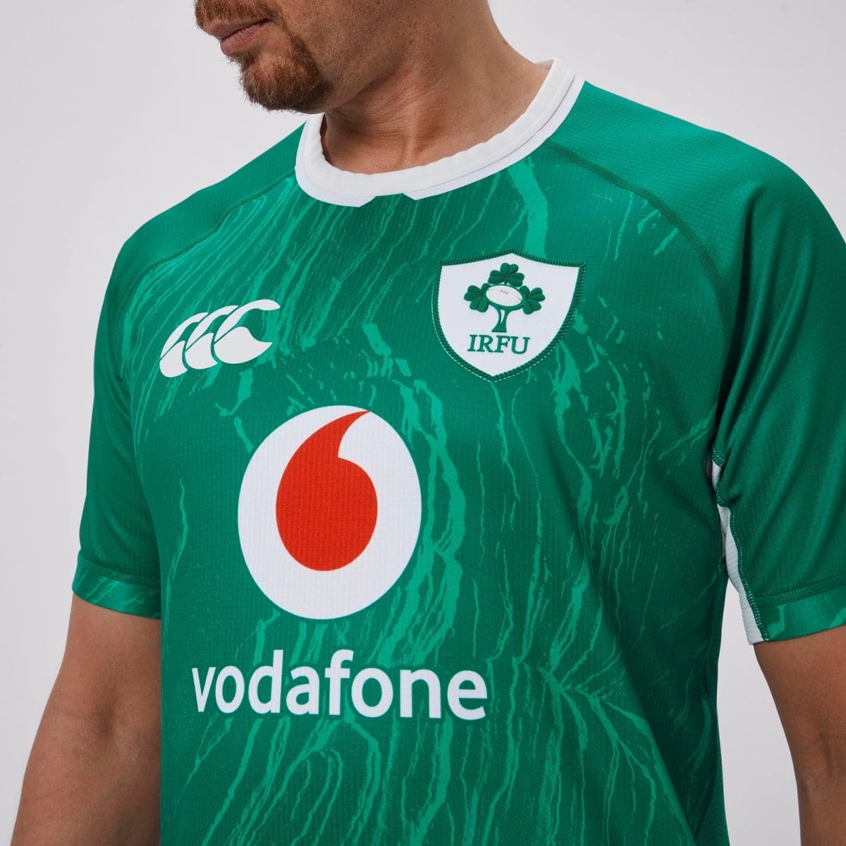 Green rugby jersey close-up showing the IRFU crest on the chest, with Vodafone sponsor logo and CCC branding nearby.