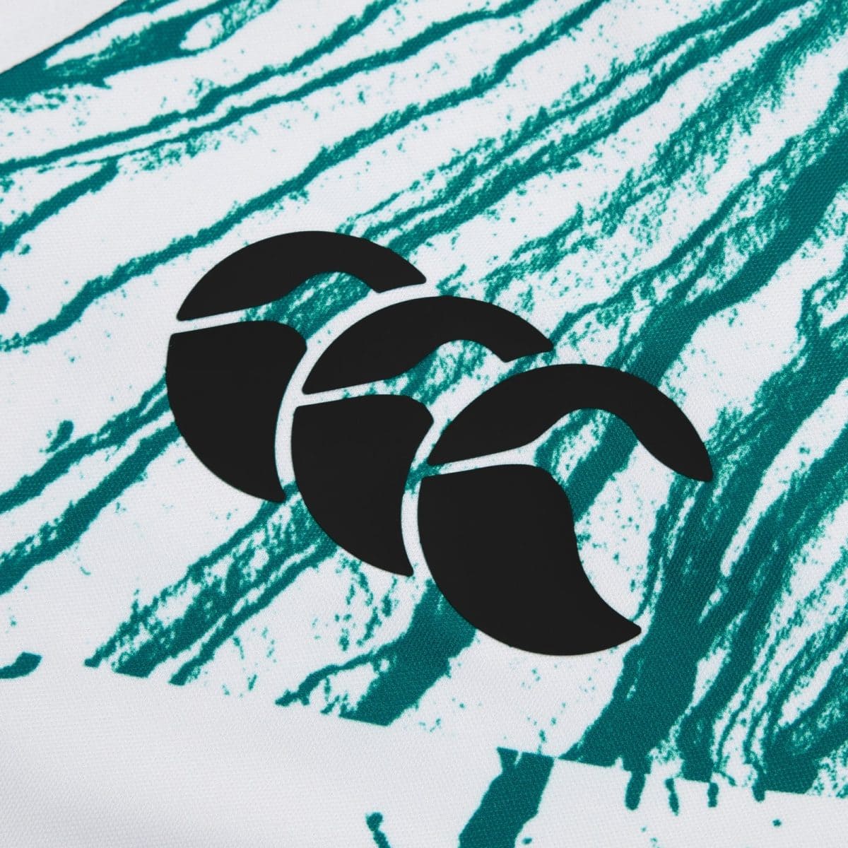 Close-up of teal brush-stroke pattern on white fabric with a partial black curved logo.