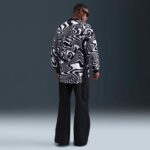 14b61f0f-954c-4e7f-9061-ba59d80ffb49 | UAE SPORT STORE Back view of a man wearing a bold black-and-white swirling-pattern shirt and black wide-leg pants, with sunglasses on.